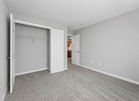 A room with a white door and a grey carpet.
